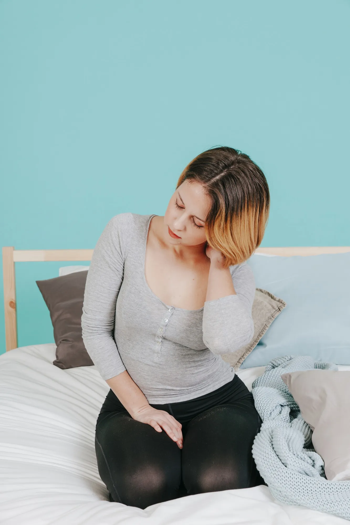 Woman touching neck on bed