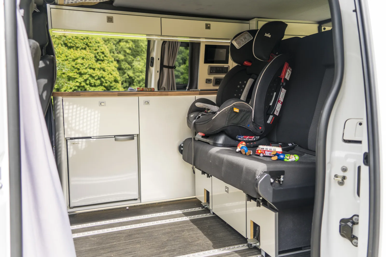 Photograph of a child's car seat in the back of a camper van about to embark on a road trip.  Children's toys are located next to the car seat.
Please use this image and provide a link back to https://www.cruiseamerica.com