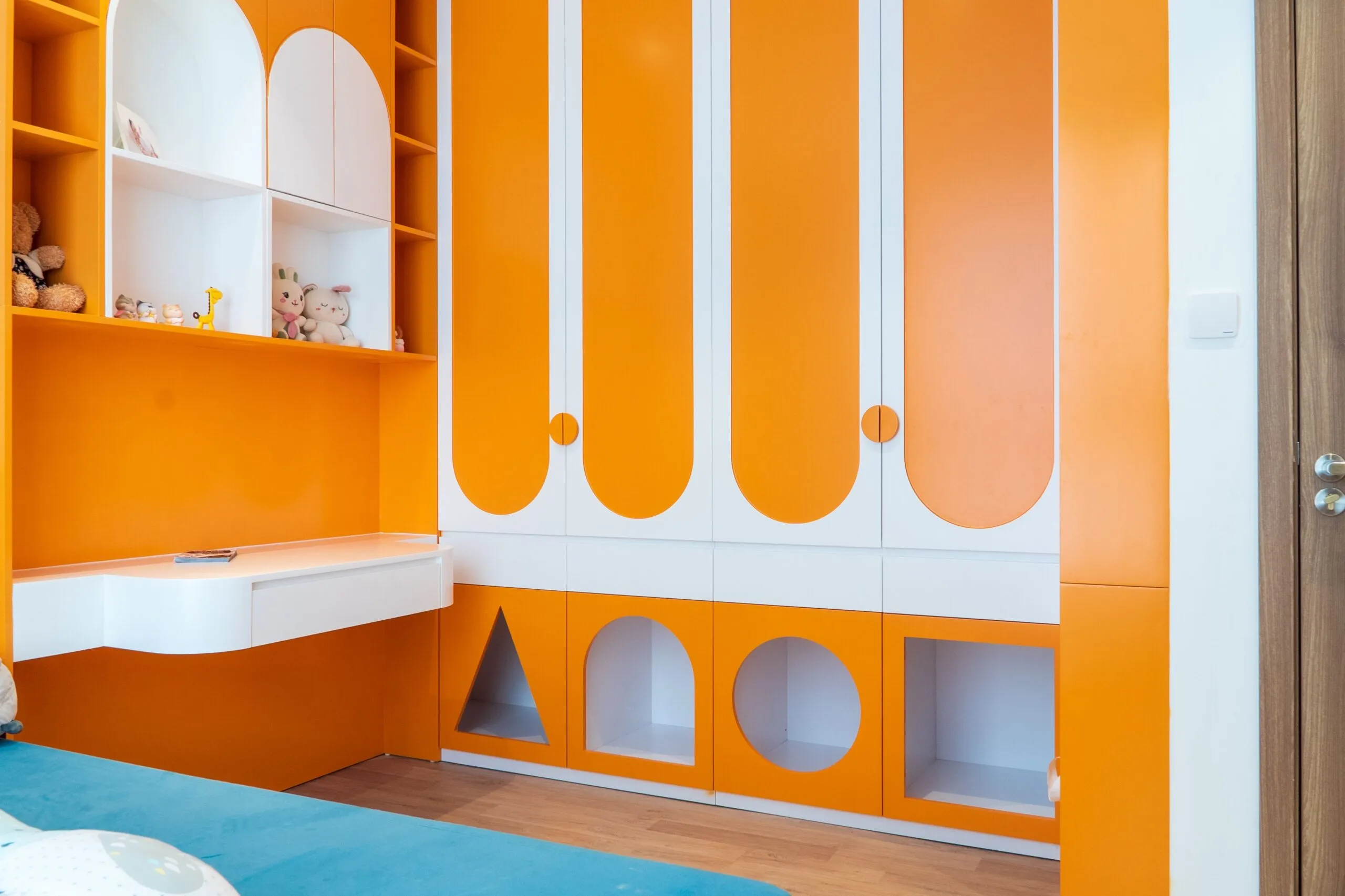 Vibrant and playful kids' bedroom with orange and white furniture featuring modern design elements.