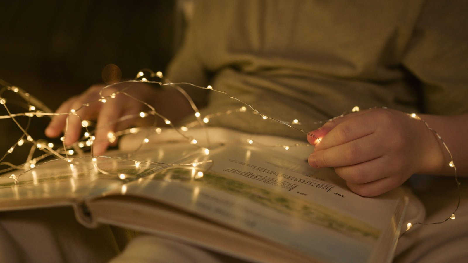 A cozy scene of a child reading a book surrounded by warm, glowing string lights.
