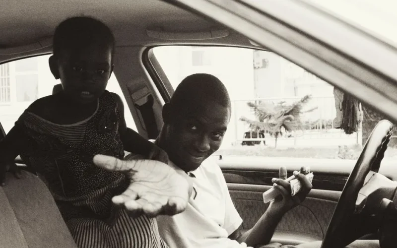 A father and child sharing a moment inside a car, captured in a warm monochrome style.