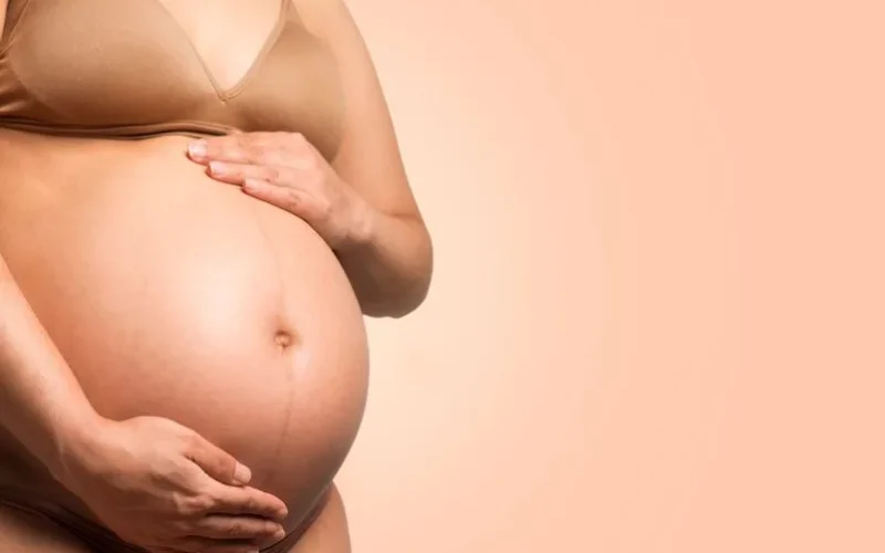 A pregnant woman gently cradles her belly, symbolizing motherhood and love.