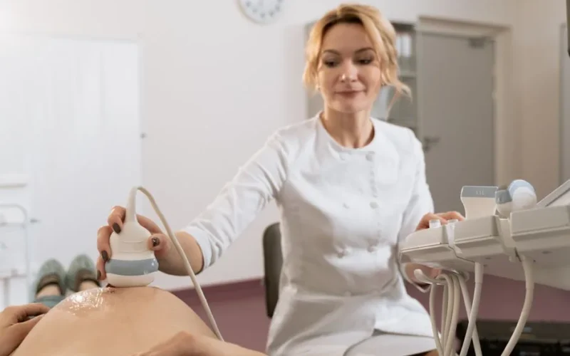 Healthcare professional performing ultrasound examination on pregnant woman in medical clinic.