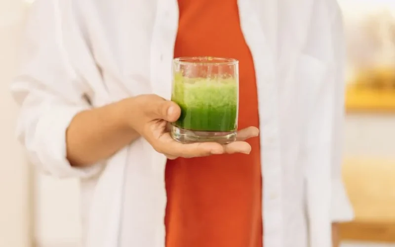 Close-up of a person holding a refreshing green smoothie, symbolizing a healthy lifestyle.