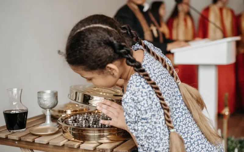 A young girl curiously looks at communion elements in a church setting.