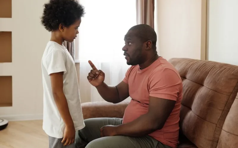 Father and son engaged in a heartfelt conversation on the sofa, illustrating parenting in a loving family setting.