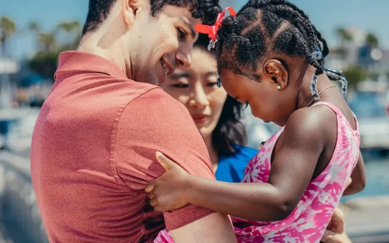 A joyful moment captured of a diverse family bonding outdoors on a bright summer day.