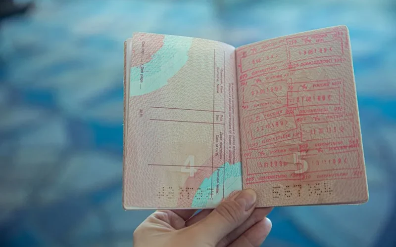 Close-up view of an open passport displaying various travel stamps in an airport setting.