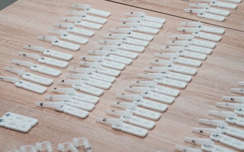 Multiple COVID-19 test kits displayed neatly on a wooden table indoors.