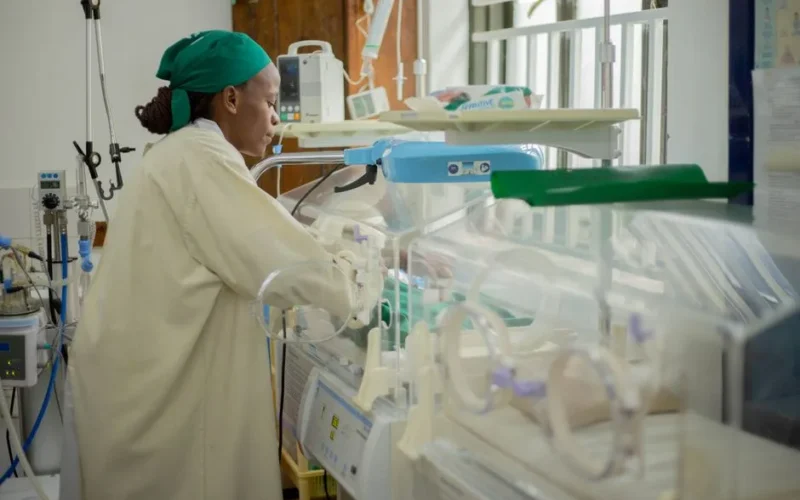 Doctor attending to newborns in an incubator in a hospital neonatal unit.