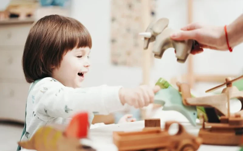 Smiling child playing and exploring with wooden toys in a bright room, fostering creativity.