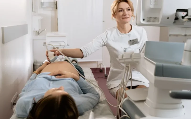 A pregnant woman receiving an ultrasound exam conducted by a healthcare professional in a medical clinic.