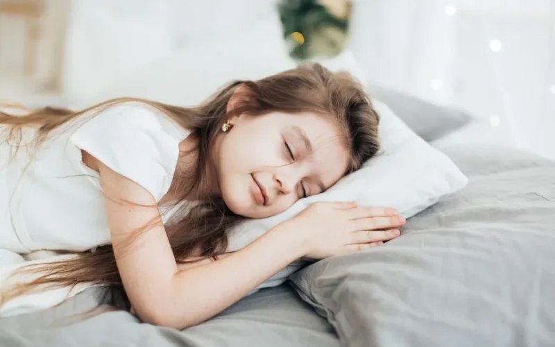A serene portrait of a young girl peacefully sleeping on a soft pillow indoors.