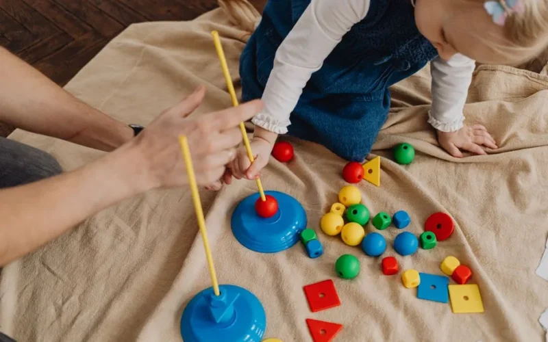 A child playing with educational toys, learning shapes and colors with a supervising adult.