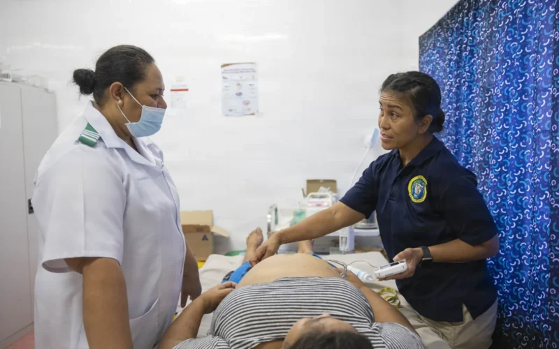 A pregnant woman receiving an ultrasound exam conducted by a healthcare professional in a medical clinic.