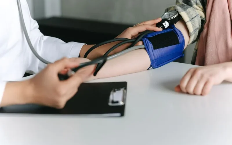 A healthcare worker uses a sphygmomanometer to check a patient's blood pressure in a medical office.