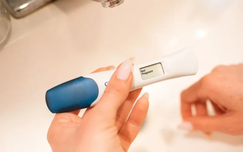 Close-up of a negative pregnancy test displayed by a woman's hand.