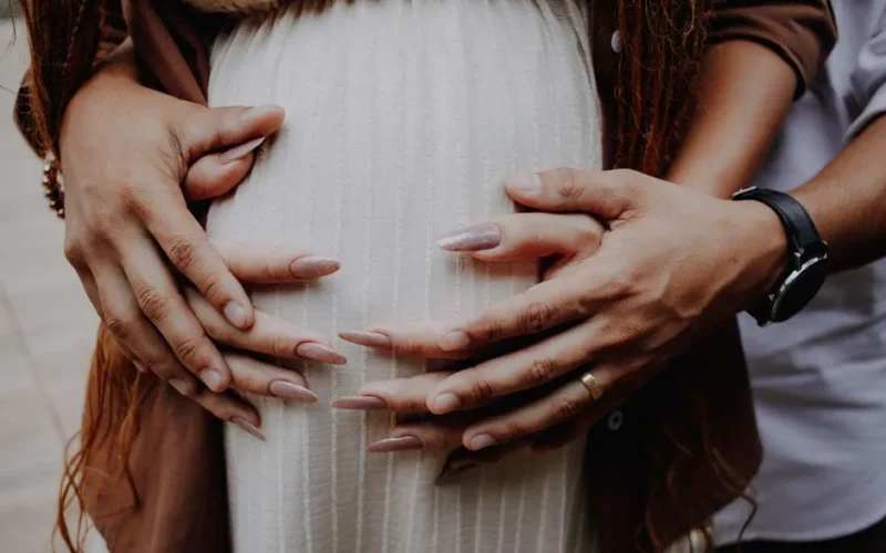 Intimate close-up of hands embracing a pregnant belly, symbolizing love and family bonds.