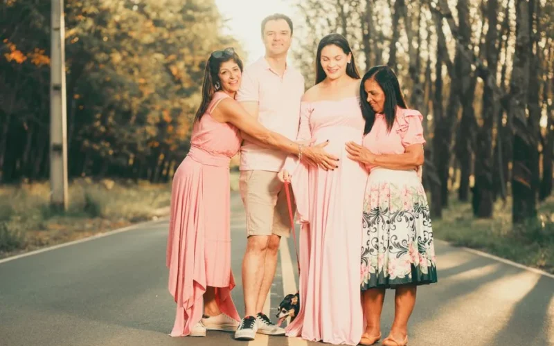 Family celebrating pregnancy on a sunlit road, showcasing joy and anticipation.
