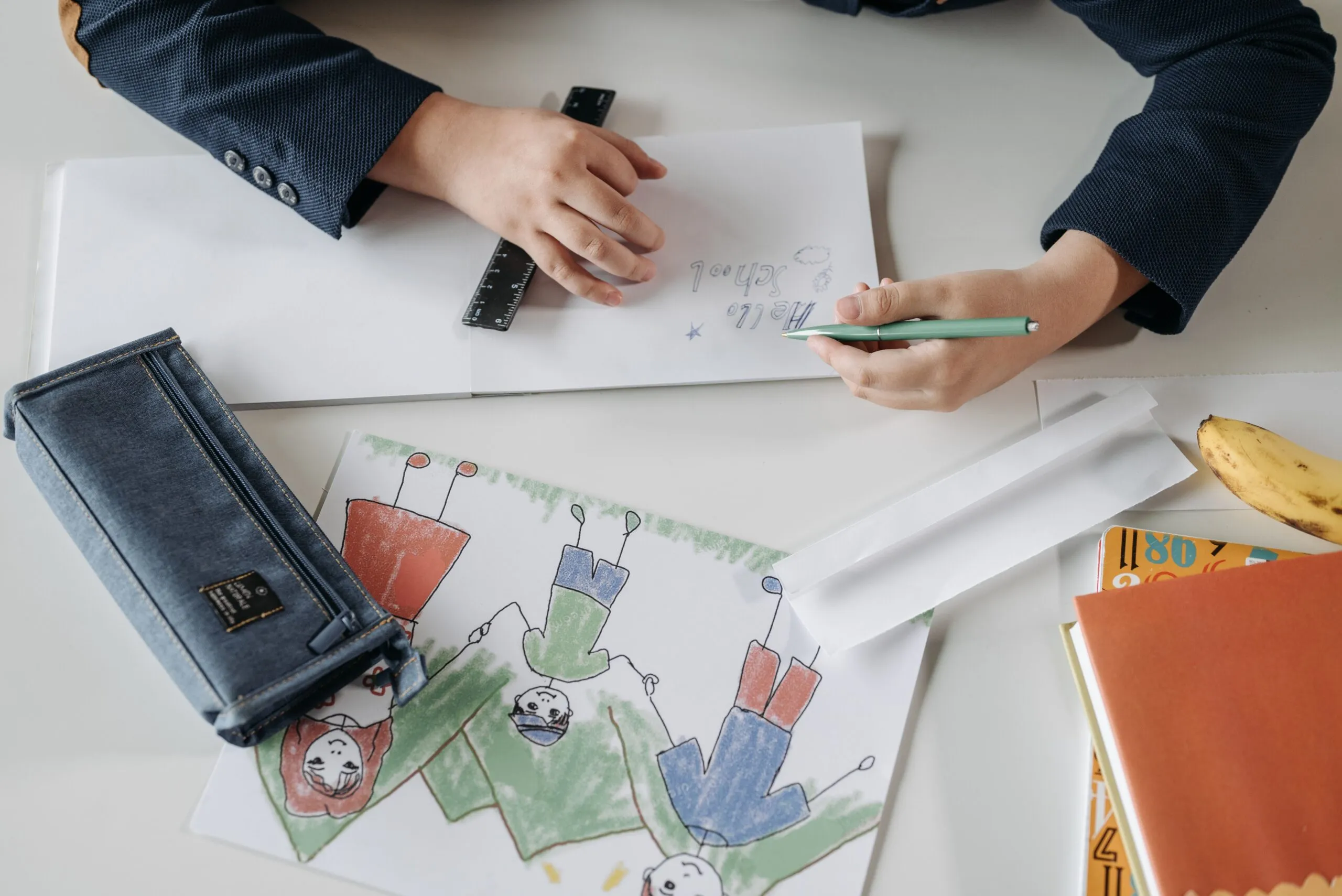 A child drawing with a pencil on a notebook, showing creativity and fine motor skills.