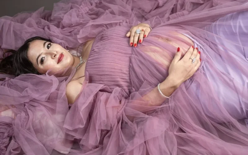 Portrait of a pregnant woman in an elegant purple gown, showcasing grace and beauty.