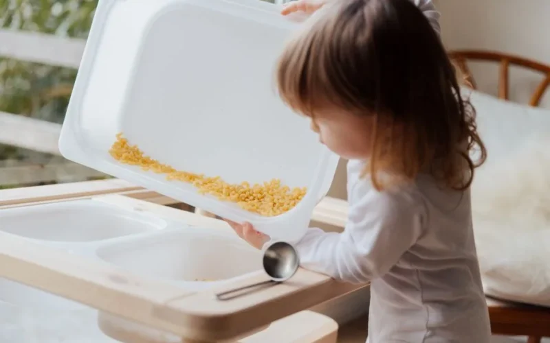 Adorable child playing with pasta in a sensory tray, focusing on fun indoor learning.