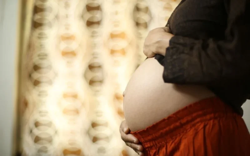 Intimate close-up of a pregnant woman's belly with hands touching, showcasing motherhood and love.