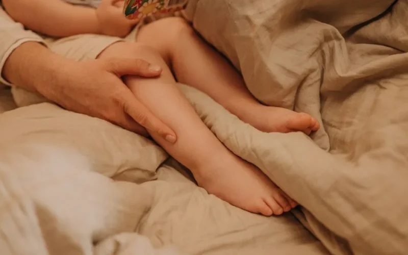 Close-up of a caregiver's hand holding a child's legs, conveying warmth and affection.