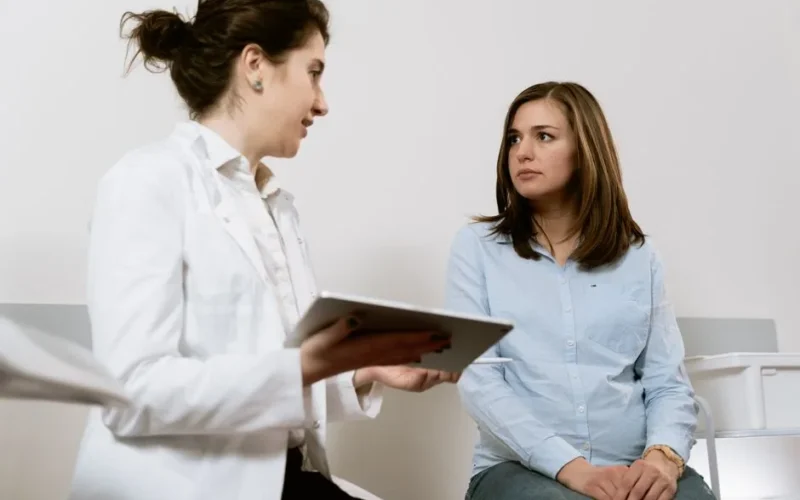A doctor consults with a pregnant patient discussing healthcare options in a medical facility.