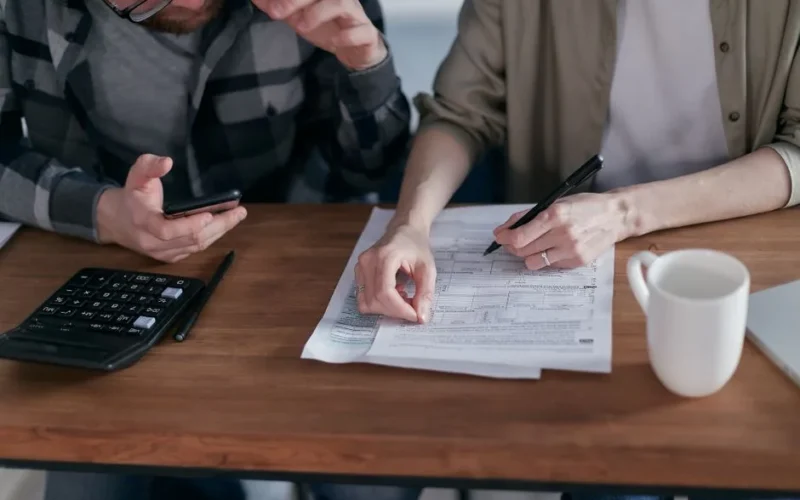 A couple collaboratively managing finances with papers and calculator in hand.