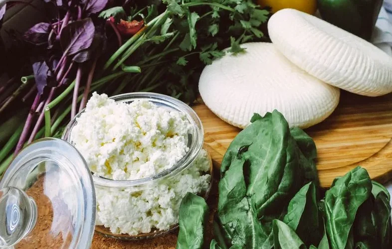 Close-up of fresh ricotta cheese, leafy greens, and bell peppers, perfect for salads and healthy recipes.