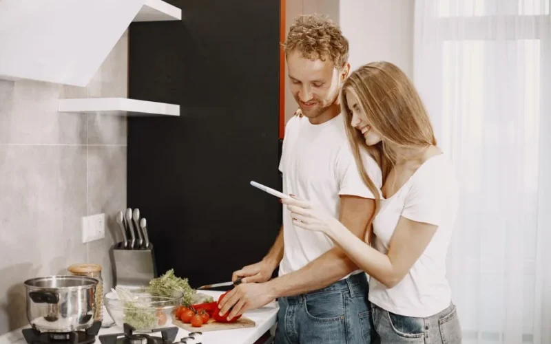 Couple happily preparing a healthy meal together in a modern kitchen setting.