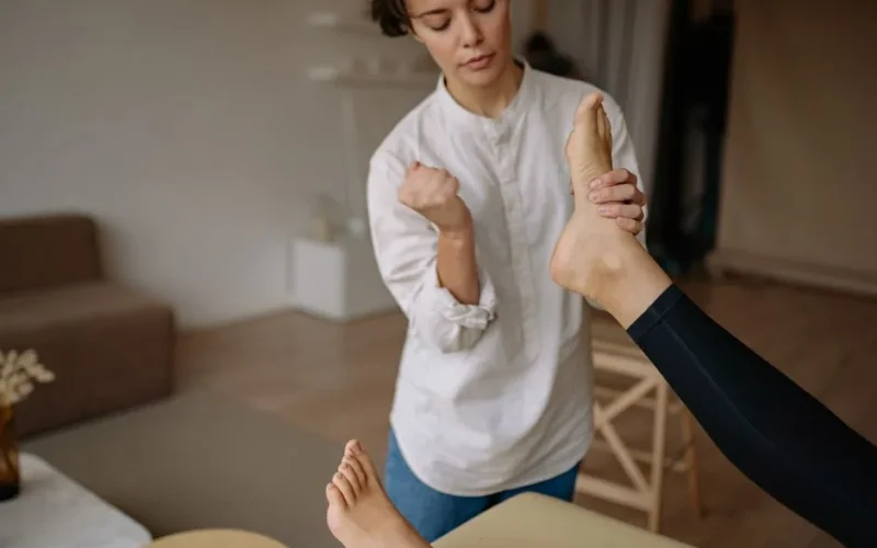 A massage therapist gives a relaxing foot therapy session in a calm indoor setting.