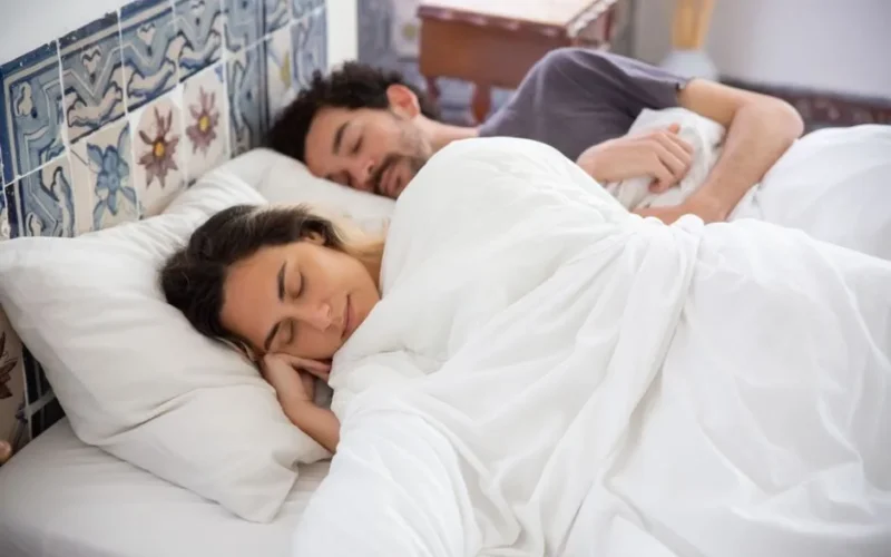 A serene image of a couple sleeping together in a cozy bedroom, capturing tranquility and comfort.