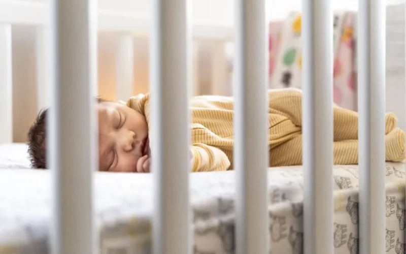 A serene image of a baby sleeping peacefully in a crib, capturing warmth and tranquility.