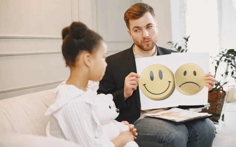 A therapist uses emotion cards to help a child express feelings during a counseling session.