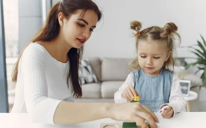 A mother and daughter bond while playing with educational toys indoors.