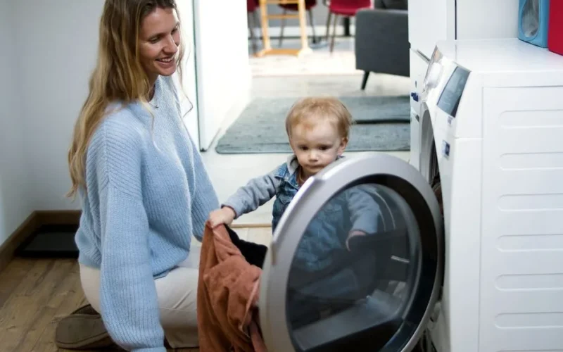 Mother and toddler joyfully doing laundry together, fostering family bonding at home.