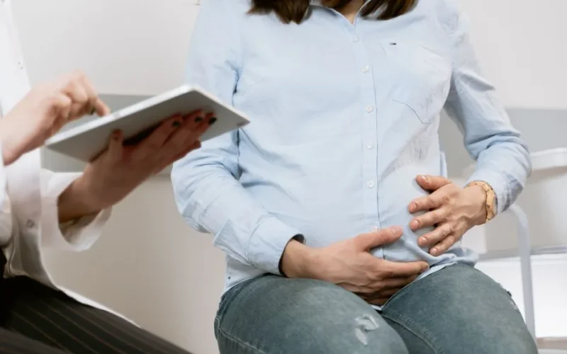 Pregnant woman attending a healthcare consultation, showcasing doctor-patient interaction.