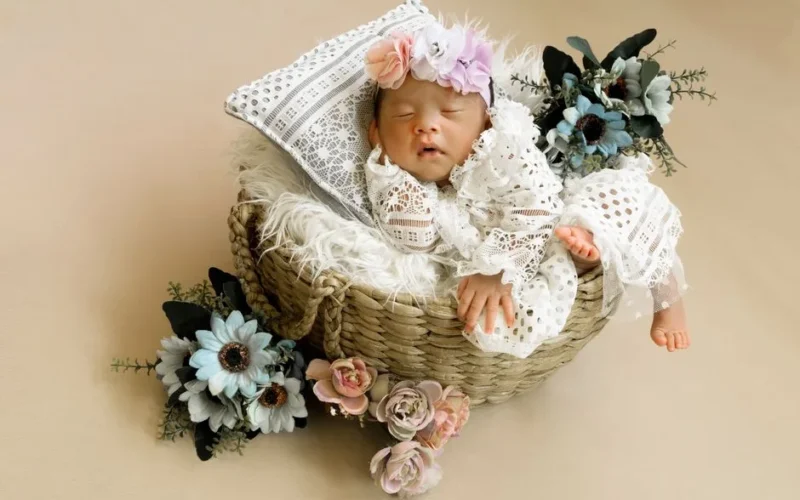 Peaceful newborn baby sleeping in a basket decorated with delicate flowers, creating a serene and heartwarming scene.