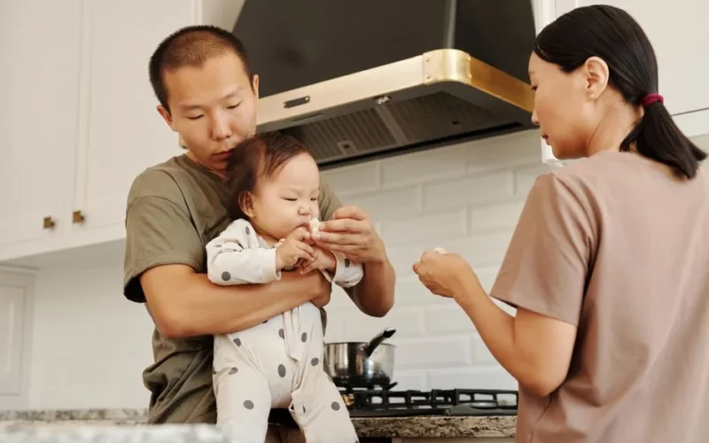Family feeding time in a cozy kitchen as parents care for their baby.