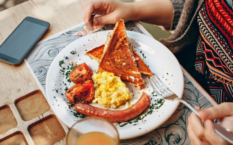 A cozy brunch scene with toast, scrambled eggs, sausage, and juice.