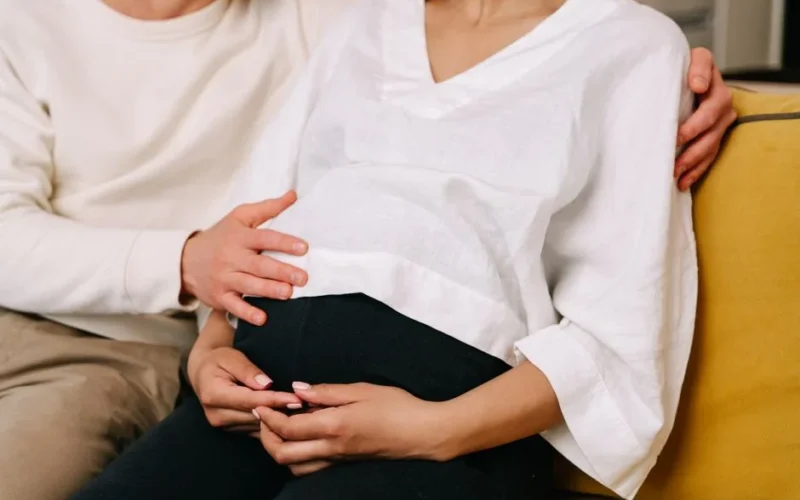 Close-up of couple embracing and touching a pregnant belly, symbolizing family and love.