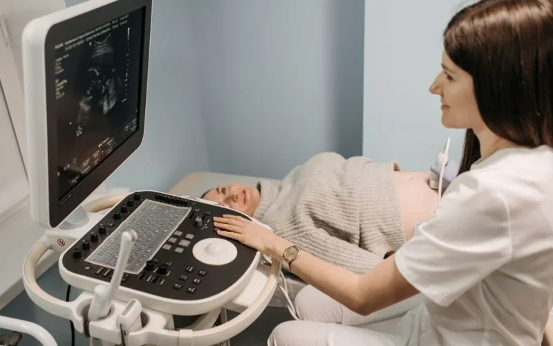 A healthcare professional performing an ultrasound on a pregnant woman in a clinic setting.