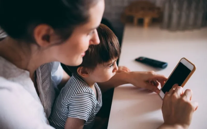 A mother and child bonding while using a smartphone at home.