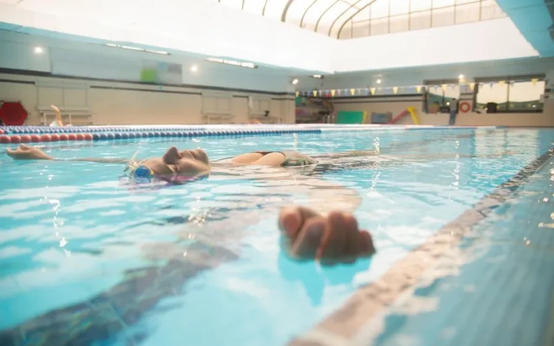 Adult woman floating peacefully in a swimming pool, enjoying a moment of relaxation.