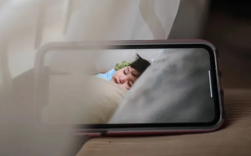 Broadcast with baby monitor of kid sleeping in crib at daytime on smartphone screen