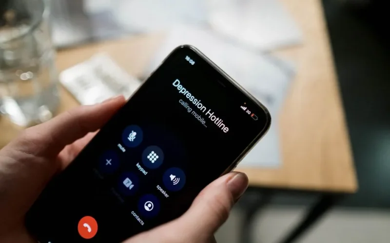 Close-up of a person holding a smartphone, calling a depression hotline.