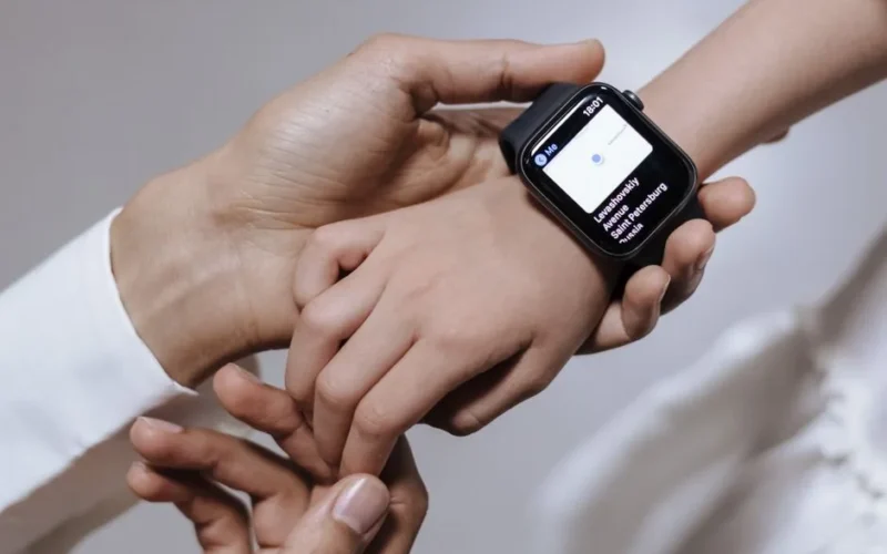 Close-up of a mother assisting her daughter with a smartwatch, emphasizing family care and technology.