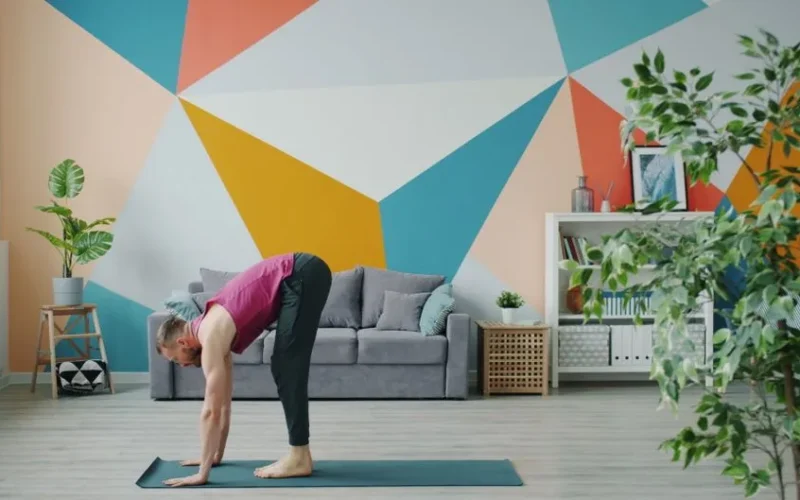 A man performing yoga in a colorful, modern living room with geometric wall art.